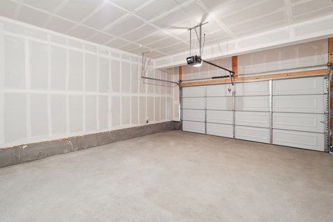 A spacious garage with a white ceiling and a light hanging from the ceiling.