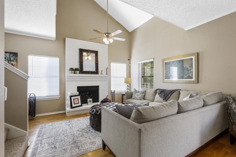 A living room with a grey couch and a fireplace.