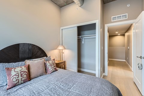 A bedroom with a large bed and a lamp on a nightstand.