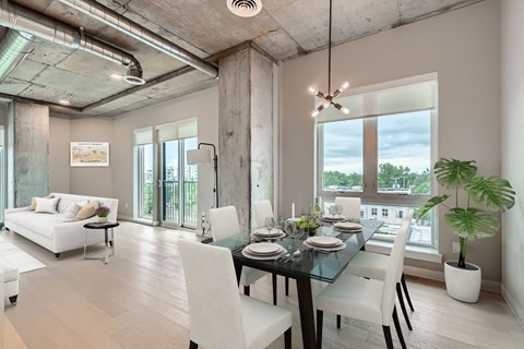 A modern dining room with a glass table and white chairs.