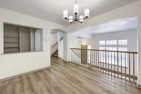 A spacious room with wooden floors and a staircase.