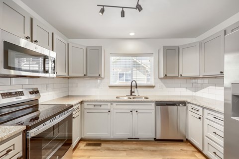 A modern kitchen with white cabinets and stainless steel appliances.