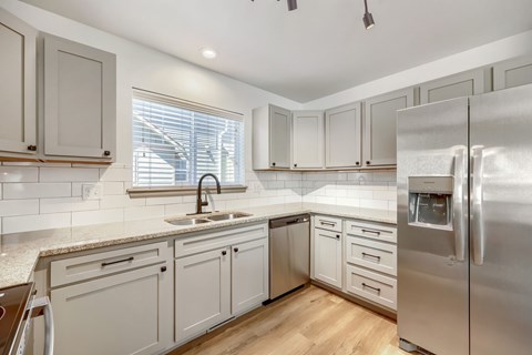 A kitchen with a sink, refrigerator, and cabinets.
