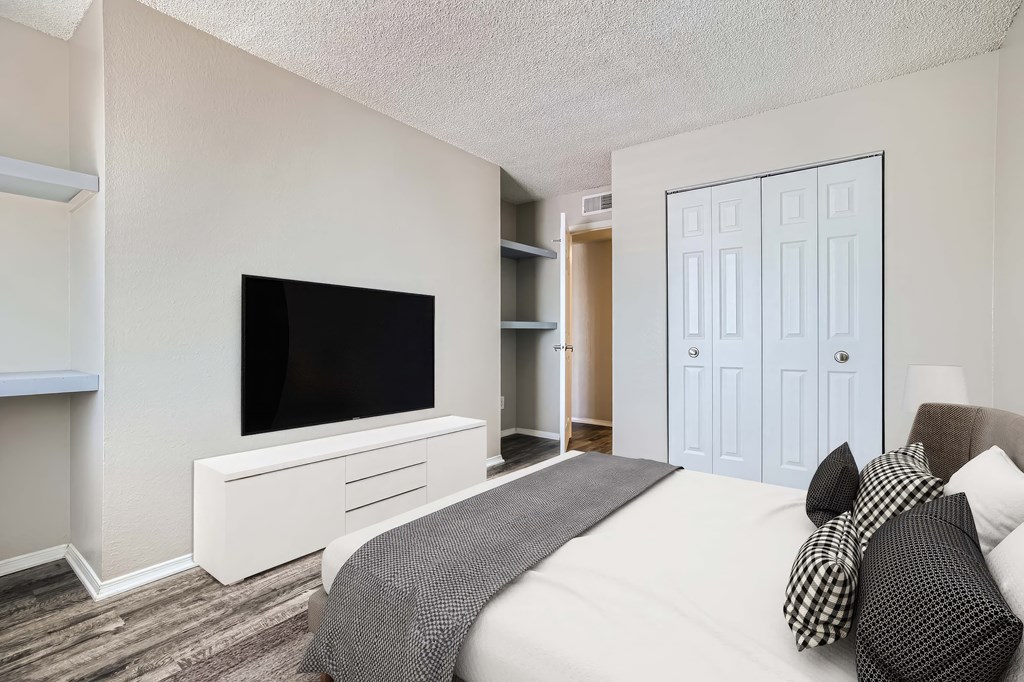 A bedroom with a bed, a television, and a wardrobe.