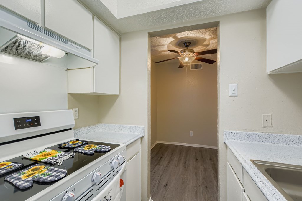 A kitchen with a white stove top oven and a fan on the ceiling.