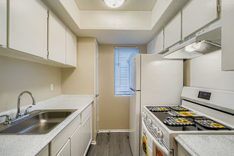 A kitchen with white cabinets and a stove top oven.