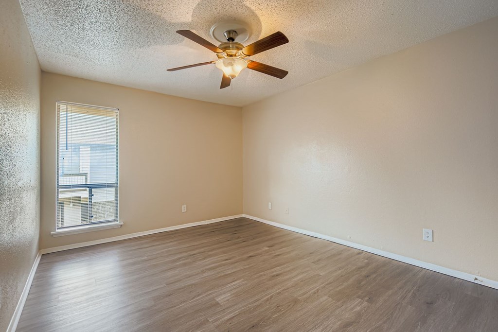 Empty room with a ceiling fan and wooden flooring.