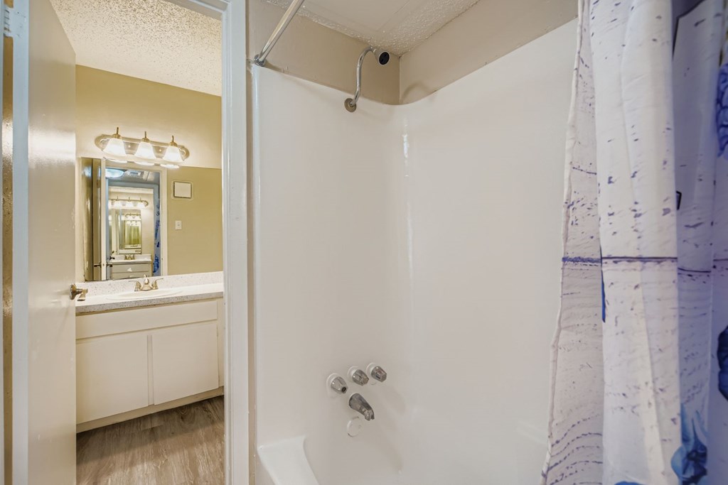 A white bathroom with a shower and a mirror.