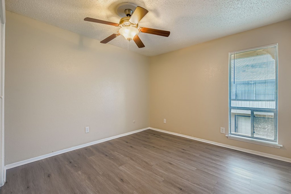 A room with a ceiling fan and a window with blinds.