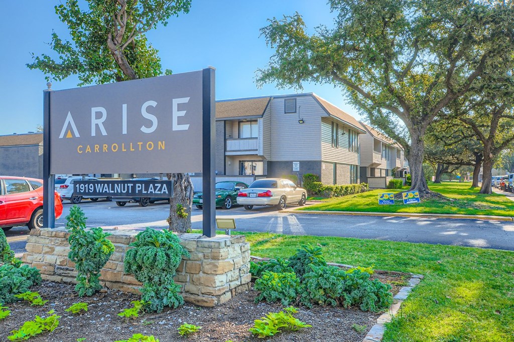A sign for Arise Carrollton stands in front of a building.