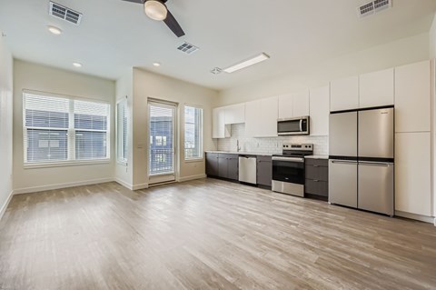 A spacious kitchen with stainless steel appliances and wooden flooring.