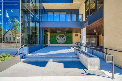 A modern building with a glass entrance and a green mural on the wall.