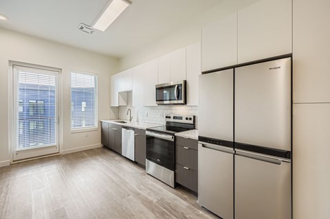A kitchen with a refrigerator, oven, and microwave.