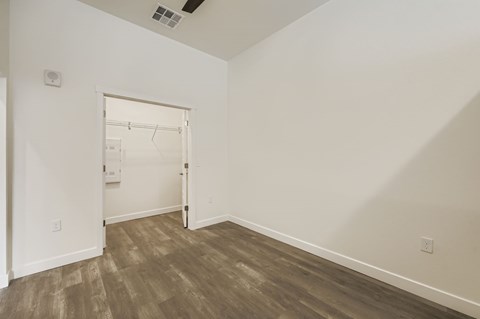 A room with a white door and wood flooring.