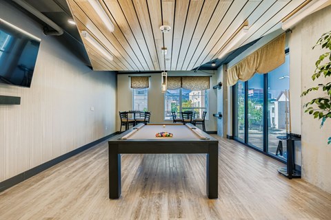 A room with a pool table and a tv on the wall.