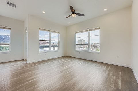 A spacious room with a ceiling fan and large windows.