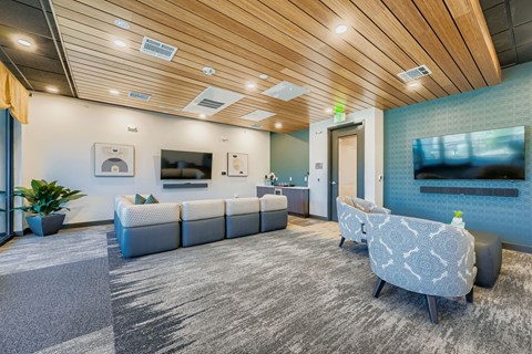 A modern waiting room with a wooden ceiling and grey carpet.