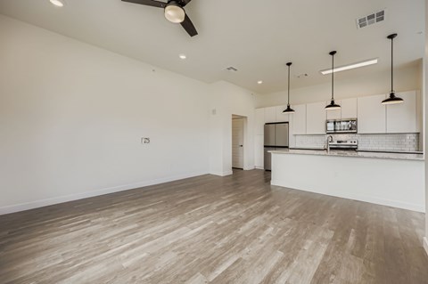 A spacious room with a bar area and a ceiling fan.