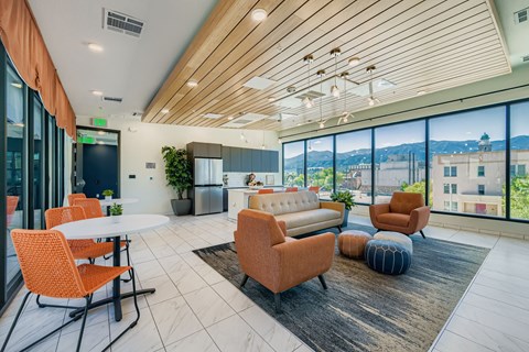 A modern living room with orange chairs and a wooden ceiling.