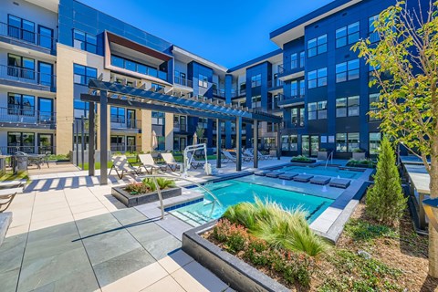 A modern building with a pool and lounge area.