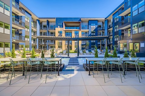 A courtyard with tables and chairs surrounded by buildings.