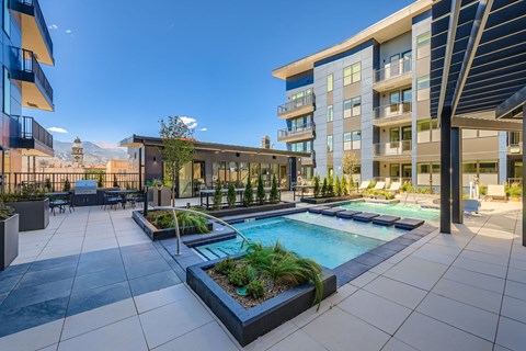 A modern outdoor pool area with a table and chairs.
