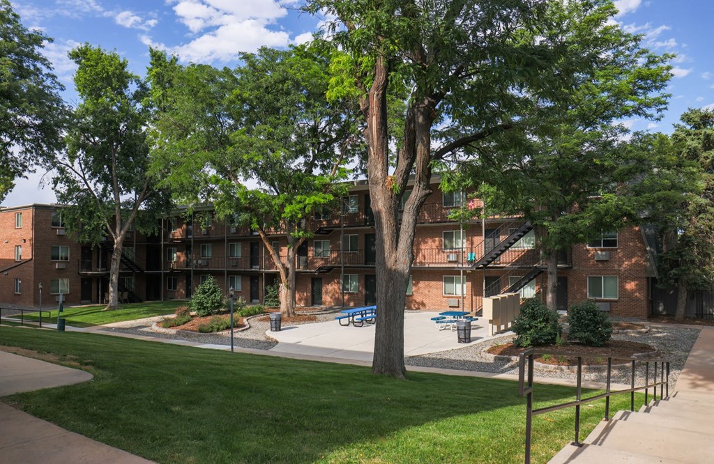 an exterior view of an apartment building with trees and a courtyard