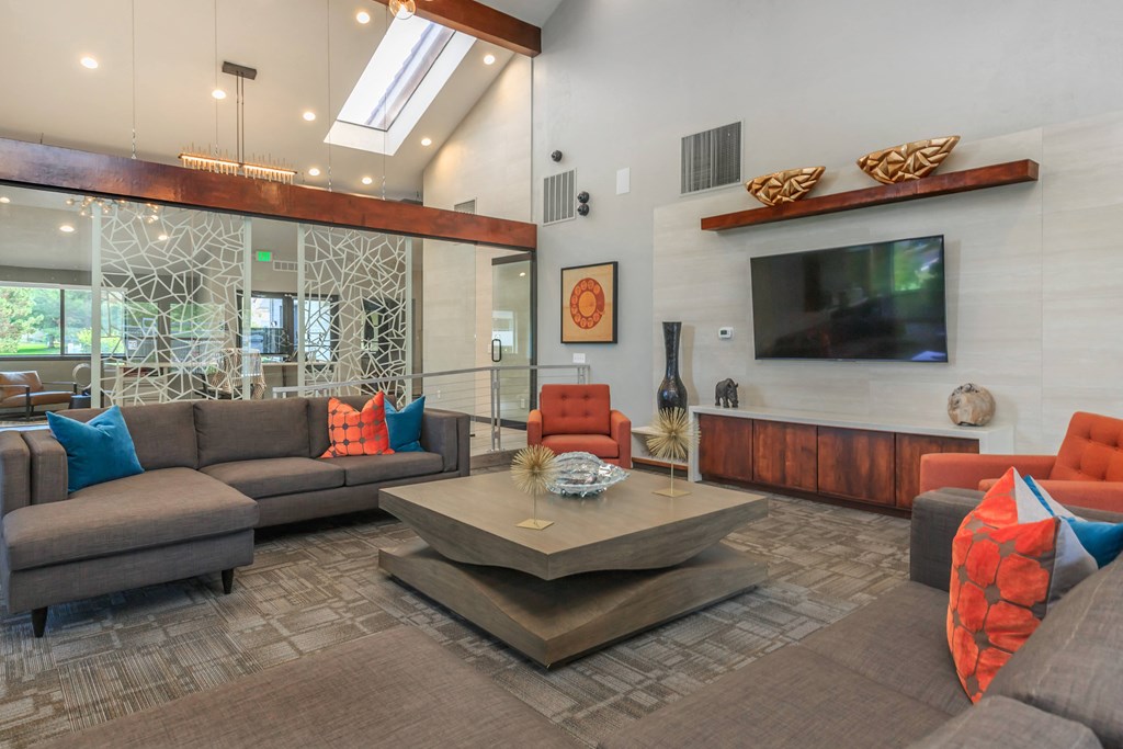 A living room with a grey couch, orange chairs, and a wooden coffee table.