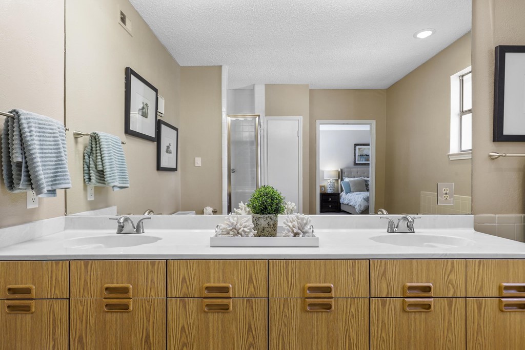 A bathroom with two sinks and wooden cabinets.
