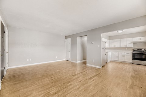 A spacious room with wooden flooring and white walls.