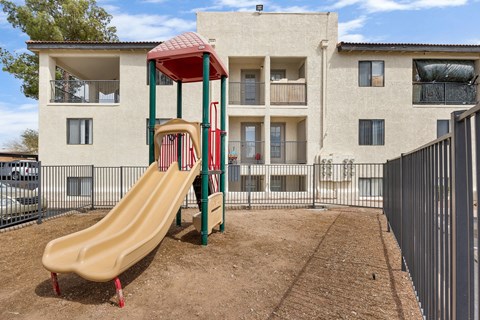 A playground with a slide in front of a building.