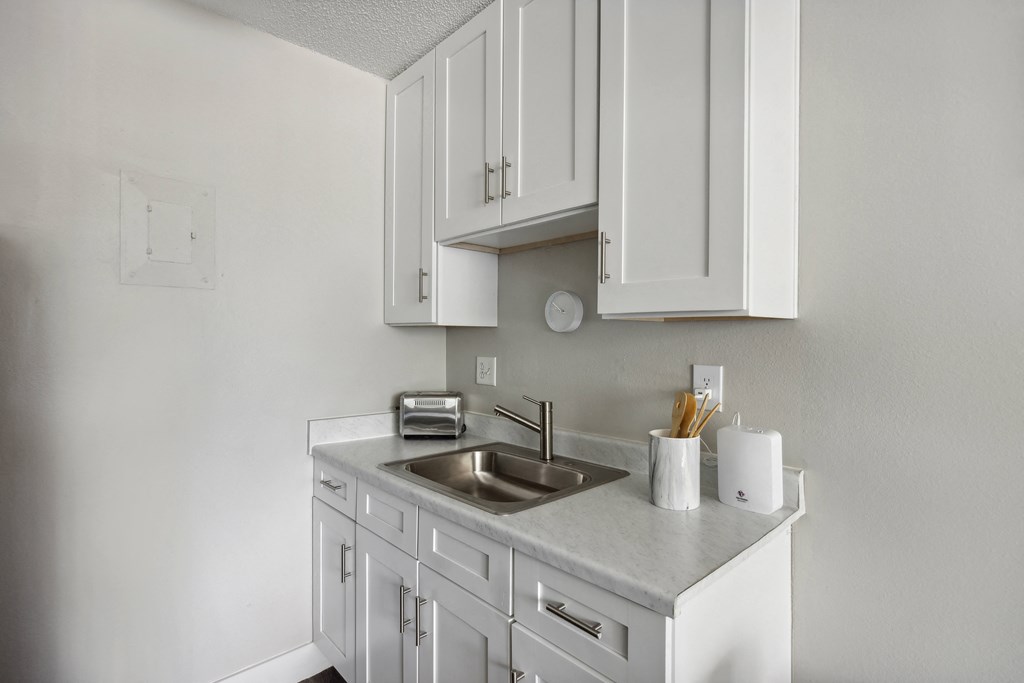 a white kitchen with a sink and white cabinets
