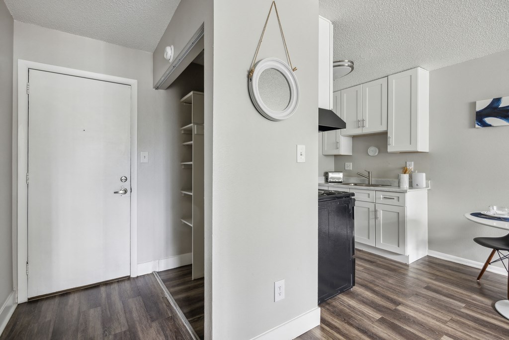 an open kitchen and living room with white walls and wood flooring