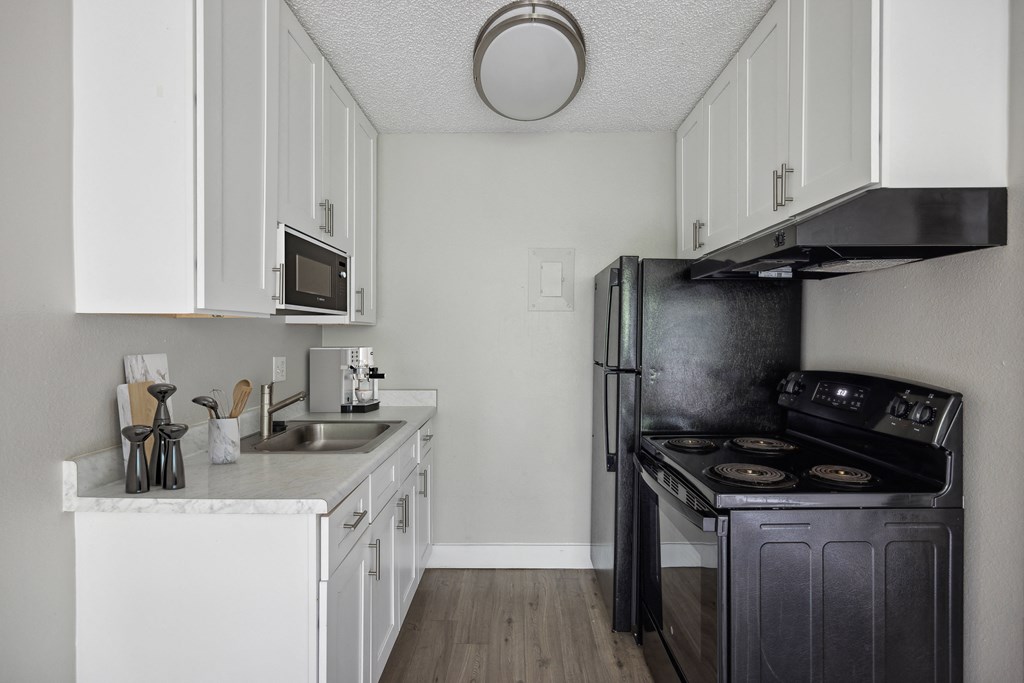 a kitchen with white cabinets and a black stove and refrigerator