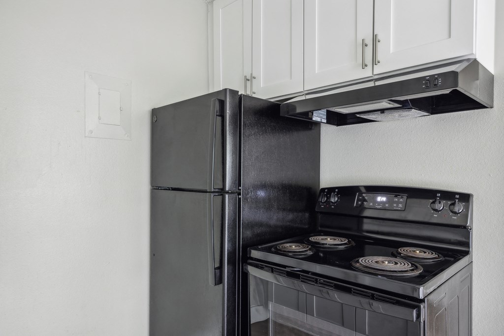 a kitchen with a stove refrigerator and white cabinets