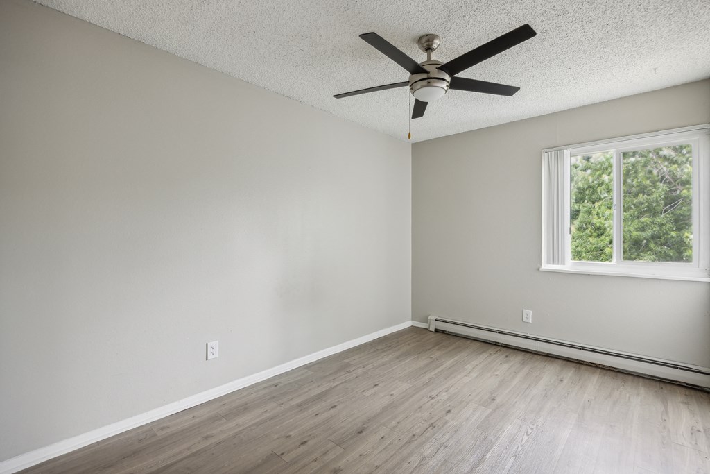 an empty room with wooden floors and a ceiling fan