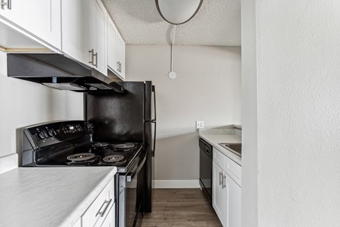 A black stove and oven in a kitchen with white cabinets.