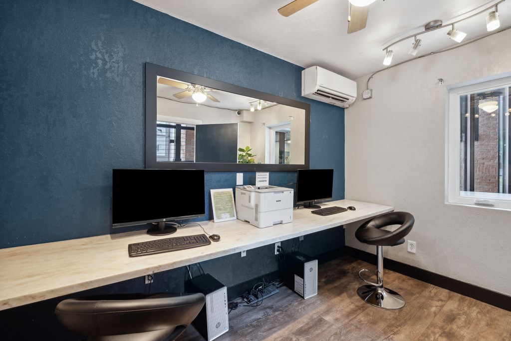 a home office with two computers and a mirror on the wall