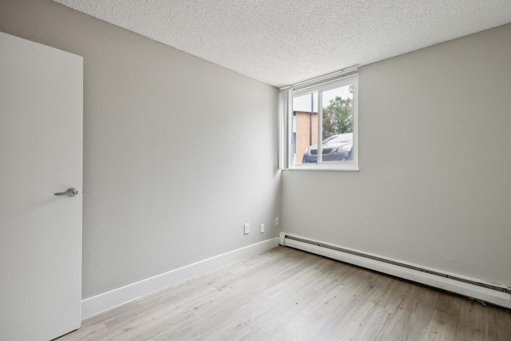 the living room of an empty apartment with wood flooring and a window