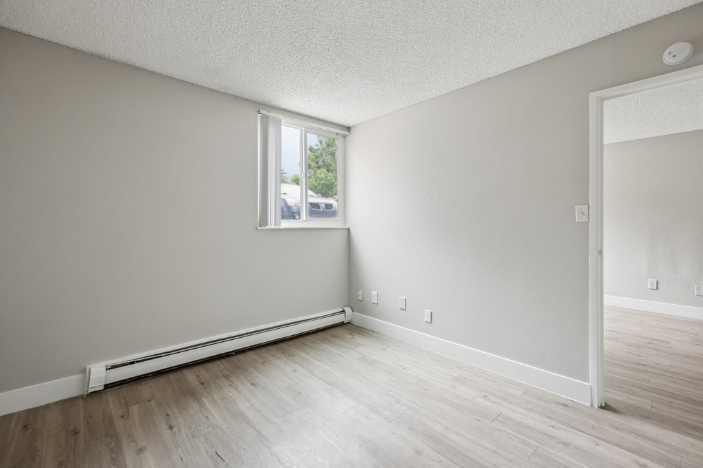 the living room of an apartment with wood flooring and a window