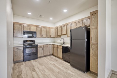 A kitchen with wooden cabinets and a black refrigerator.