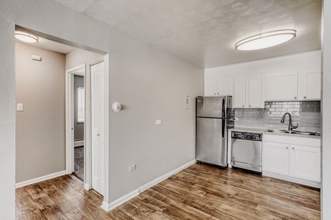A kitchen with white cabinets and a wooden floor.