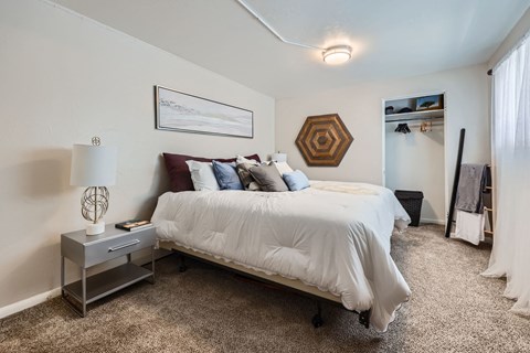A bedroom with a bed, nightstand, and a painting on the wall.