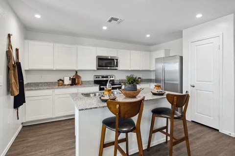 A kitchen with white cabinets and a wooden table.