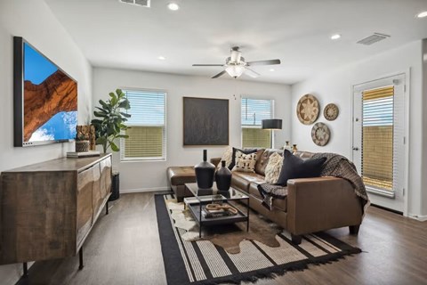 A living room with a brown couch, a coffee table, and a painting on the wall.