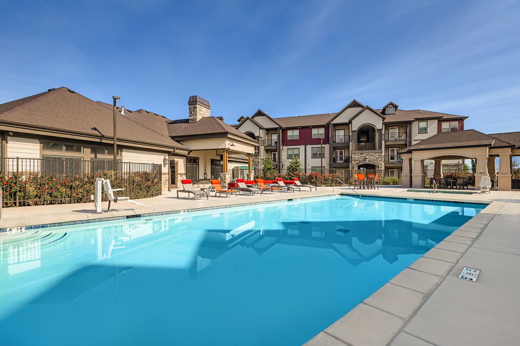 A large swimming pool in front of a building with a clear blue sky above.