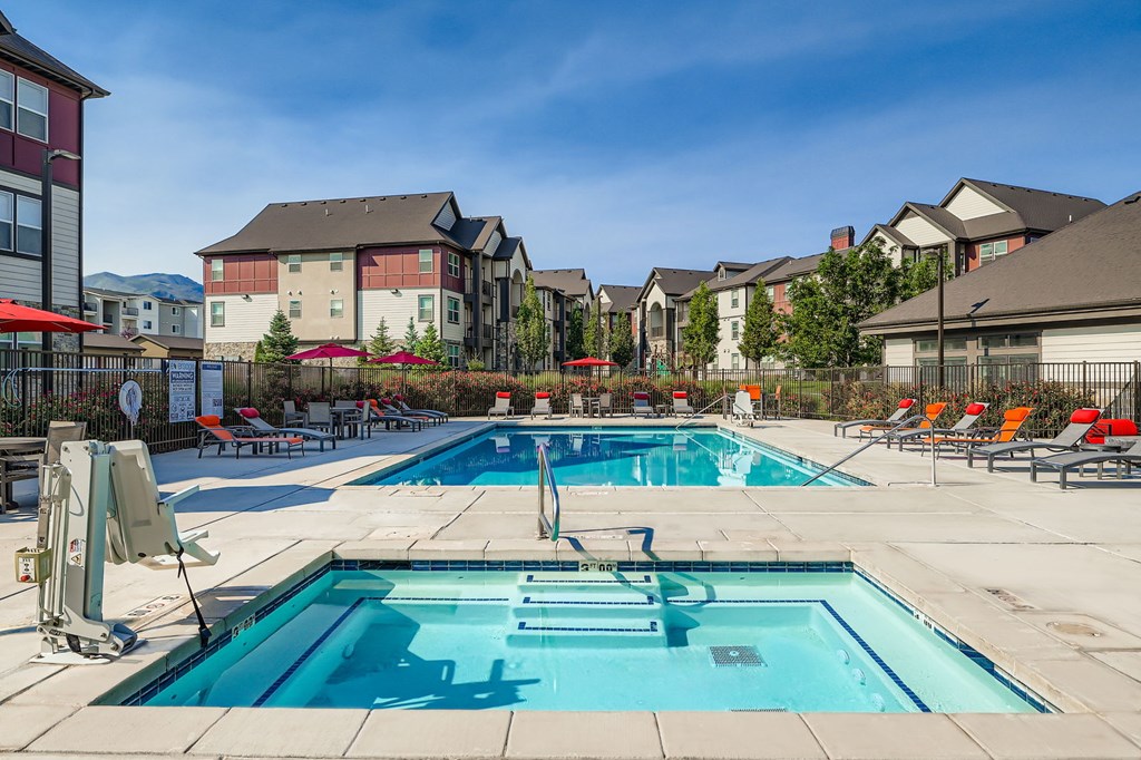 A swimming pool surrounded by lounge chairs and buildings in the background.