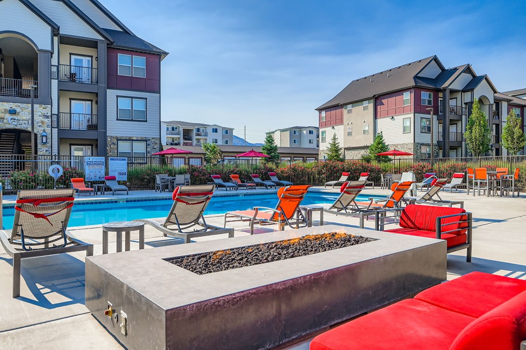 A poolside area with red chairs and a fire pit.