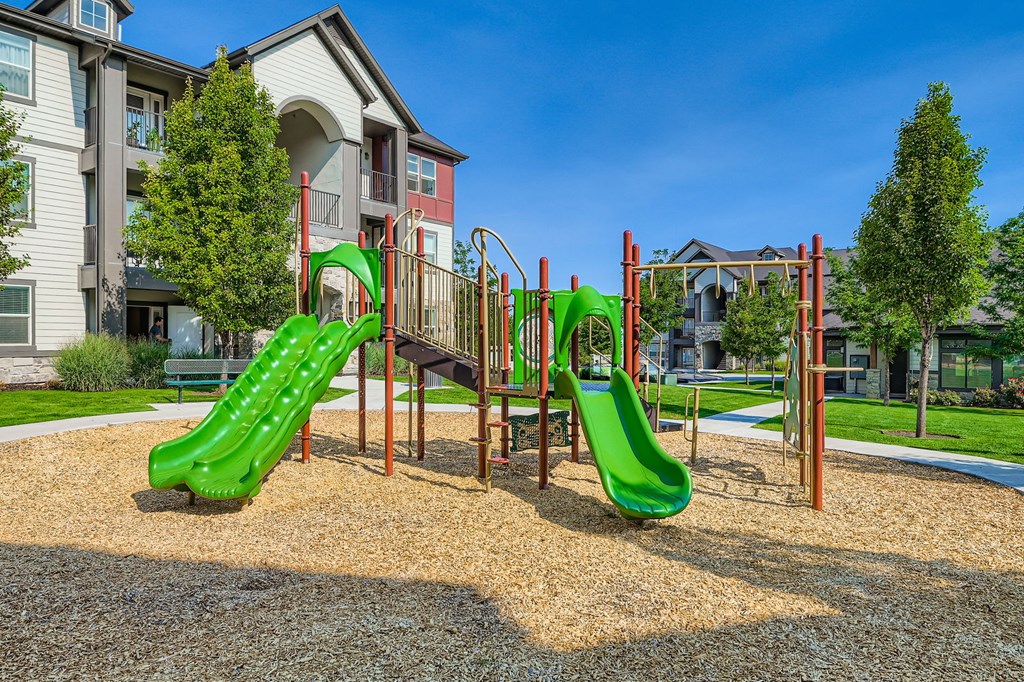 A playground with a green slide and a red structure.