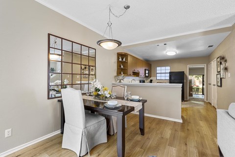 A dining room with a table set for two and a kitchen area in the background.